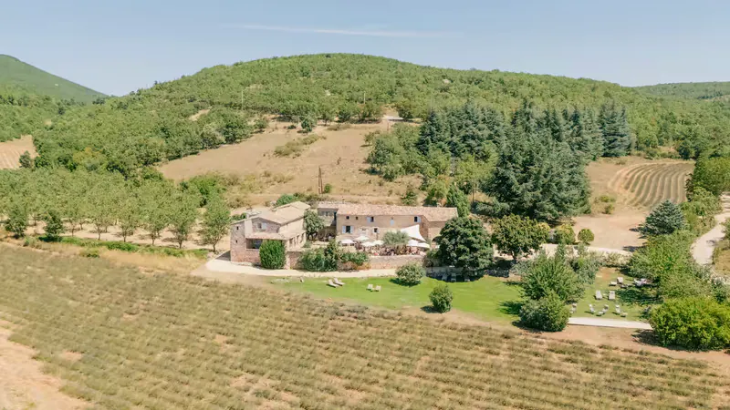 Aerial view of Le Hameau de l'Esperelle among wooded hills and lavender fields
